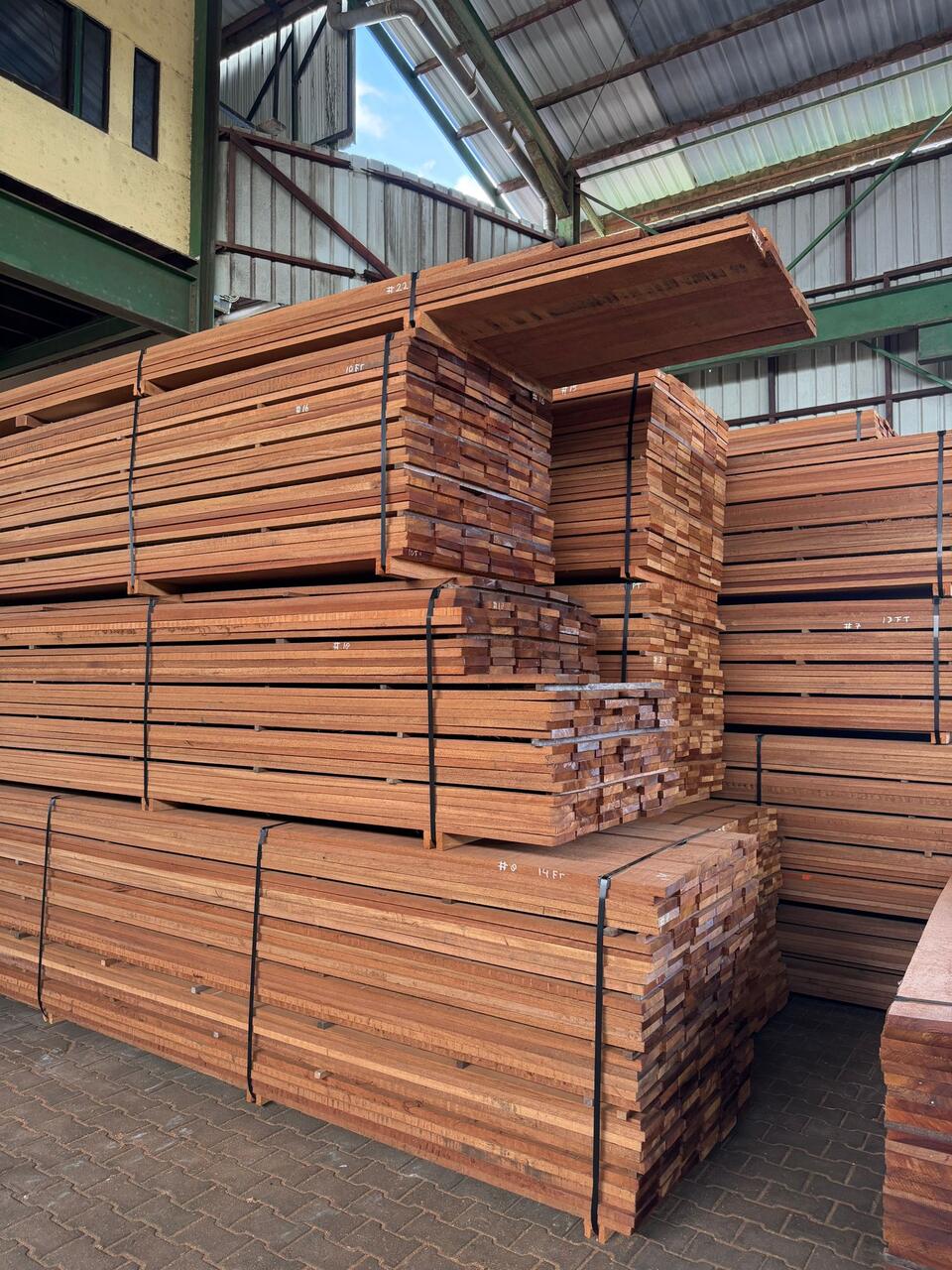 Pilas numeradas de madera tropical aserrada en el almacén